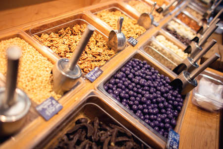 Many different nuts are sold on the counter in the store. Large selection of nuts for sale. Self service in an exotic storeの写真素材