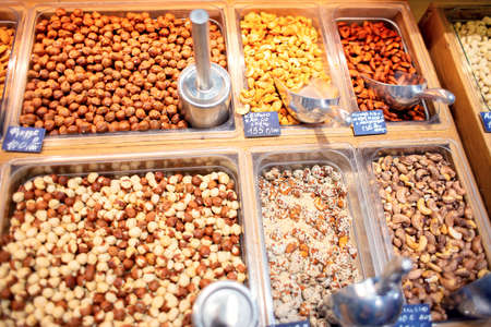 Many different nuts are sold on the counter in the store. Large selection of nuts for sale. Self service in an exotic storeの写真素材