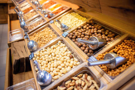Many different nuts are sold on the counter in the store. Large selection of nuts for sale. Self service in an exotic storeの写真素材