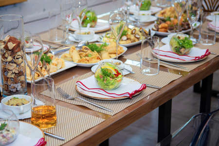 Festive table setting. Fancy salad plates in the shape of an aquarium. Beautiful decoration of the banquet table. Glass transparent dishesの写真素材