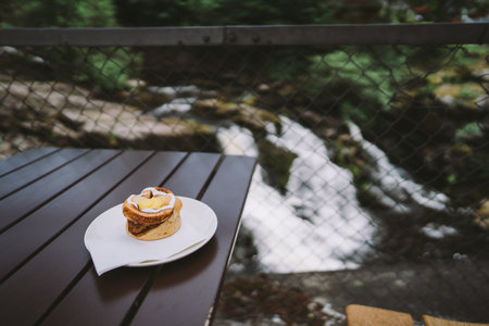 Tasty pancakes on a white plate on a wooden table against the background of a waterfallの写真素材