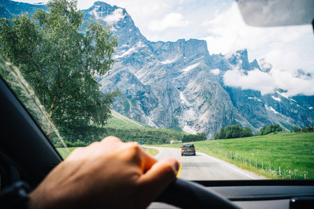Scenic Drive through Majestic Mountain Road with Lush Greenery and Dramatic Peaks on a Clear Summer...