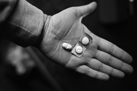 Close Up of Hand Holding Medicine Pills in Monochrome Light Highlighting Healthcare and Personal Use