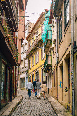 Charming Urban Scene with Tourists Strolling Through Narrow Cobblestone Alley Between Vibrant...