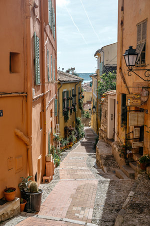 Charming Mediterranean Alleyway with Colorful Buildings and Potted Plants on a Sunny Day in a Quaint...
