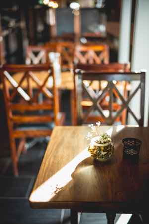 Cozy Sunlit Cafe Interior with Wooden Tables and Chairs Featuring a Decorative Tabletop Arrangement