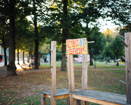 Colorful Handcrafted Pop-Up Shop Sign in Tranquil Urban Park Setting with Autumn Foliage