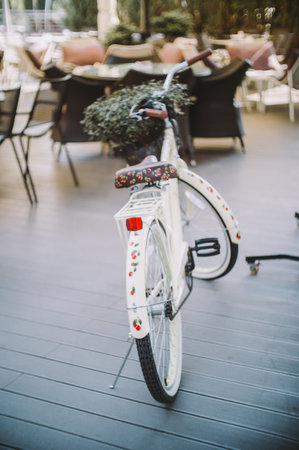 Vintage Style Bicycle with Floral Details in a Cozy Outdoor Patio Cafe Setting Perfect for Relaxationの写真素材
