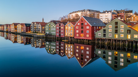 Scenic View of Colorful Wooden Houses on Stilts Reflecting in Waterfront of Trondheim Norway