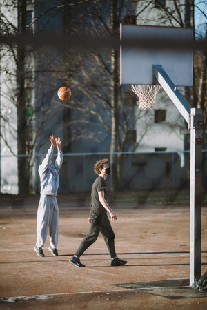 Two Young Individuals Enjoy Outdoor Basketball Game on a Sunny Day at Urban Court