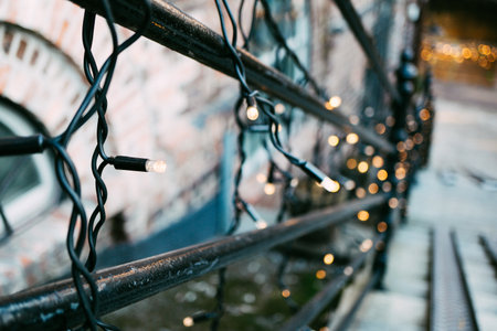 Charming Festive String Lights Elegantly Draped Over Rustic Urban Balcony Railing Creating Warm...