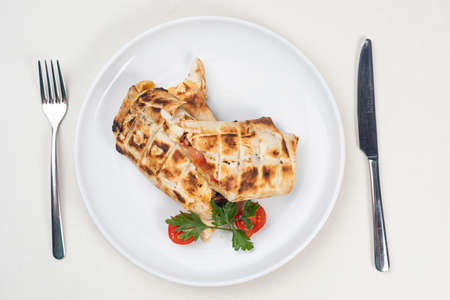 Khachapuri with cheese and tomatoes on a white plate