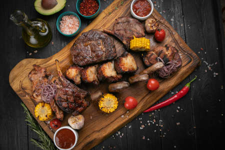 Assorted delicious grilled meat with vegetable and herbs on rustic tableの写真素材