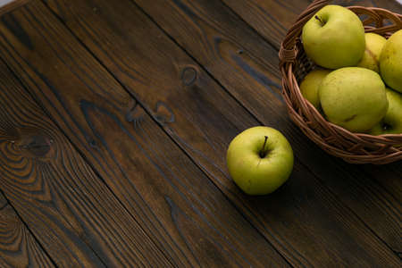 Green apples in the basket on brown wooden backgroundの写真素材