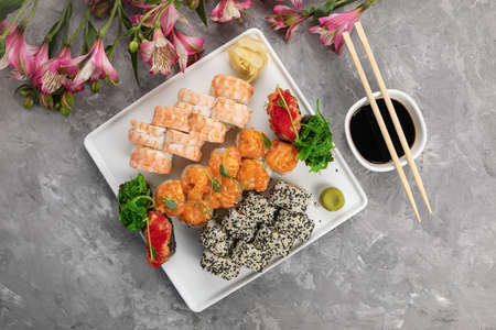 Assorted rolls with sauce and chopsticks on a gray backgroundの写真素材