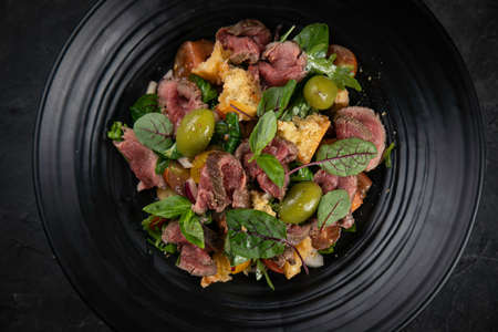 Salad with veal, olives, herbs on black backgroundの写真素材