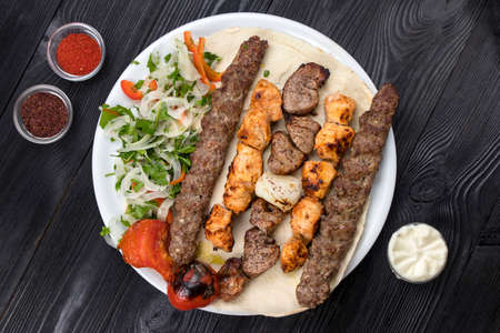 grilled meat on pita bread with salad on a black wooden backgroundの写真素材