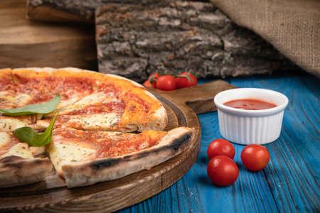 margarita pizza with tomatoes, herbs and sauce on wooden boardの写真素材