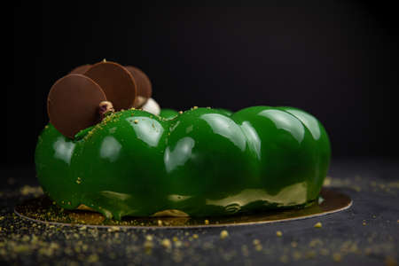 Premium mousse desserts with pistachios and chocolate on a dark backgroundの写真素材