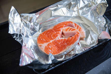 Raw salmon steak on gray board and black backgroundの写真素材