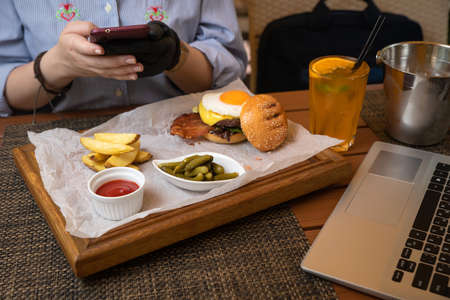 hamburger with cutlet, cheese, sauces, salad and french fries on a wooden backgroundの写真素材