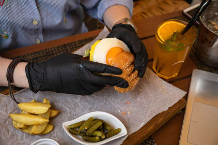 hamburger with cutlet, cheese, sauces, salad and french fries on a wooden background
