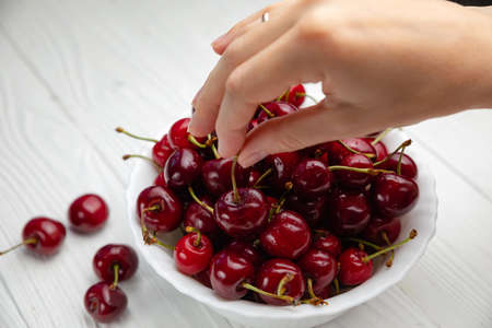 Isolated young woman holding a some cherries in her hands. Big red cherries on a white background