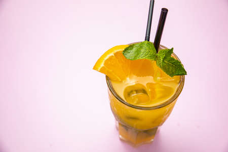 smoothie with orange on a pink table. Decorated with mint, ice. Healthy food for breakfast and snackの写真素材
