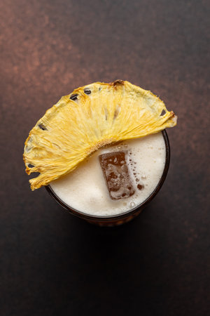 Pineapple cocktail with ice cubes on dark background. Top viewの写真素材