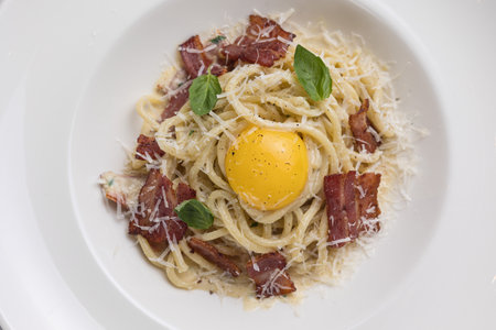 Spaghetti Carbonara with bacon and egg yolk on white plateの写真素材
