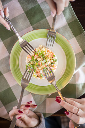 Close up of female hands holding fork and knife and eating fresh saladの写真素材
