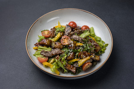 Salad with beef, vegetables and sesame seeds on a plateの写真素材