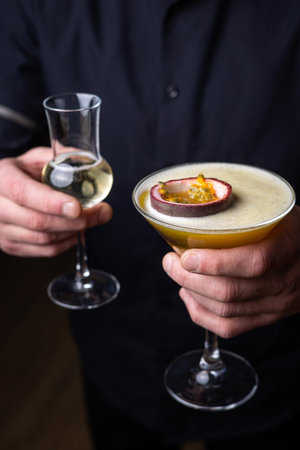 Man holding a glass of passion fruit martini cocktail with passion fruit