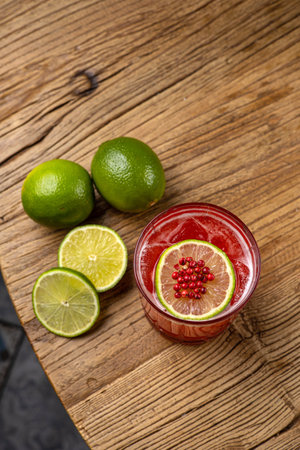 Tequila cocktail with lime and pomegranate seeds on wooden backgroundの写真素材