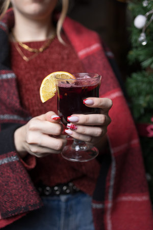 Female hands holding a glass of mulled wine with a slice of lemonの写真素材