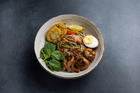 Rice noodles with pork, egg and vegetables in bowl on dark background