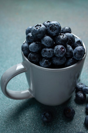 Blueberries in a cup on a blue background. Selective focus.の写真素材