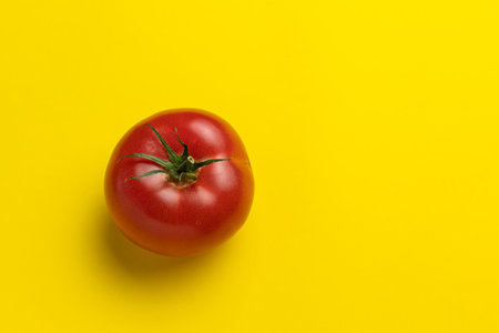 Fresh red tomato on yellow background, top view, copy space.の写真素材