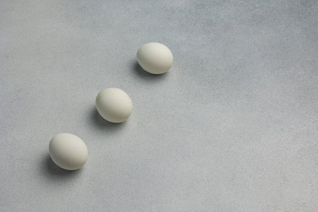 Three white eggs on a gray background. Top view. Copy space.の写真素材