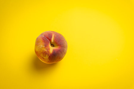 Peach on a yellow background. Top view. Copy space.の写真素材