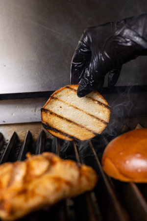 Chef's hands in black gloves cooking a sandwich on the grillの写真素材