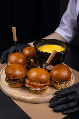Hamburgers on a wooden board in the hands of a chefの写真素材