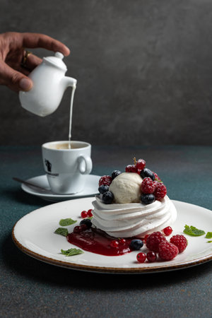 Pavlova cake with fresh berries and whipped cream on a white plateの写真素材