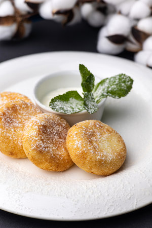 Cottage cheese pancakes with sour cream and mint on a black background
