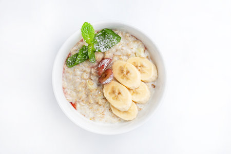 Oatmeal porridge with banana on white backgroundの写真素材
