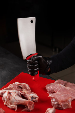 Butcher cutting meat with a large knife in a restaurant kitchen.