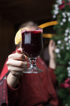 Woman holding a glass of mulled wine with a slice of lemonの写真素材