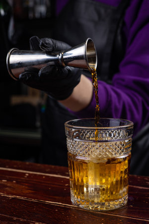 Barman pouring a cocktail from a steel shaker into a glassの写真素材