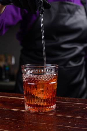 Bartender pouring a cocktail into a glass with ice cubes.の写真素材
