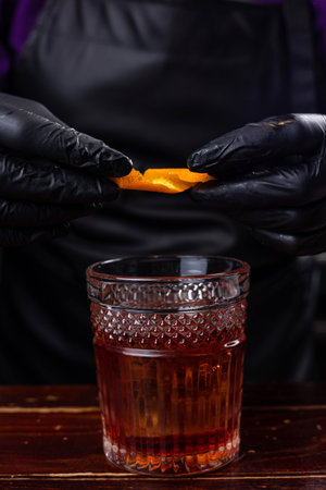 Barman hands in black gloves holding a glass of whiskey with iceの写真素材